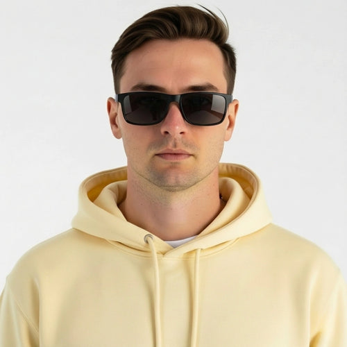 Homem usando óculos de sol quadrados com armação preta e lentes escuras, look casual com moletom amarelo