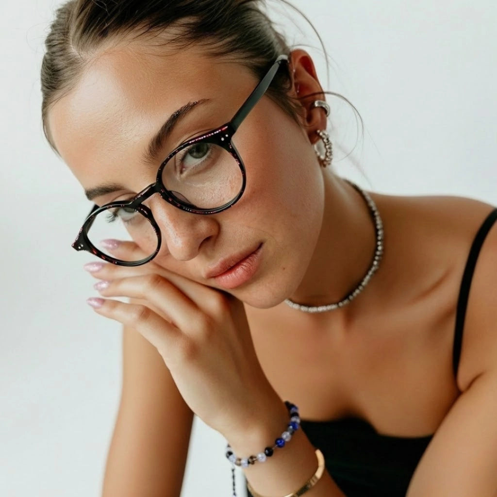 Mulher usando óculos de grau redondos com armação preta e detalhes brilhantes, estilo moderno e elegante